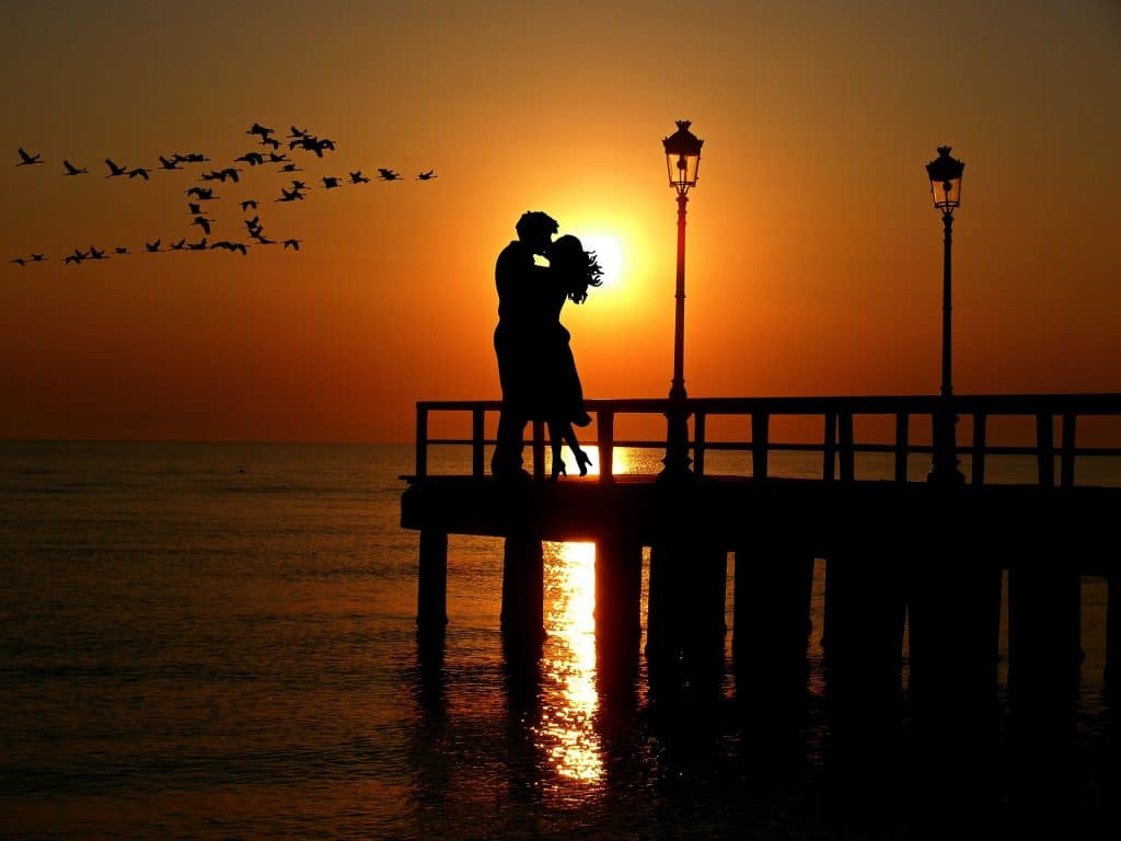 Liebespaar im Mai Sonnenuntergang auf einem Steg im Meer